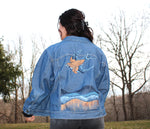 Load image into Gallery viewer, jean jacket painted with a swallow and hills landscape
